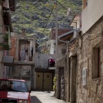 Narrow stone alley with a red car and rocky hillside