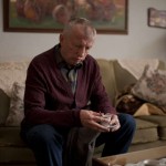 Older man in burgundy sweater on a couch