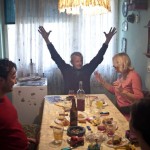 Man raising arms at a crowded dining table